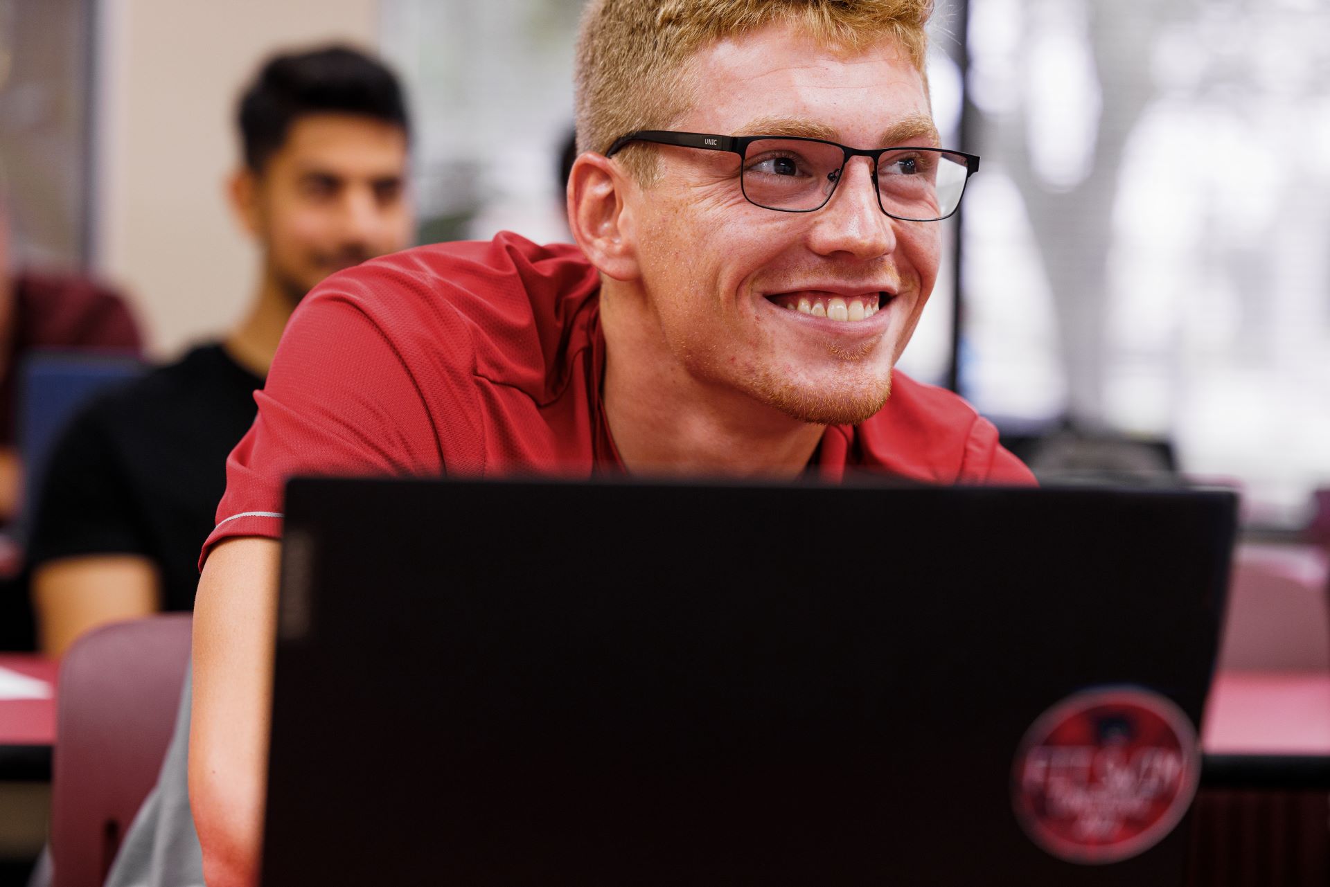 Smiling student with a laptop in a classroom
